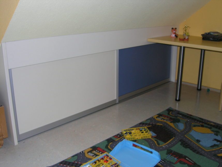 farbiges Schiebetürenregal im Kinderzimmer in der Dachschraege